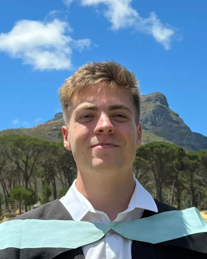 Mikael Pretorius outdoors, a mountain and pine trees behind him